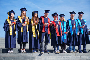 Graduates posing in front of university building on graduation day ...