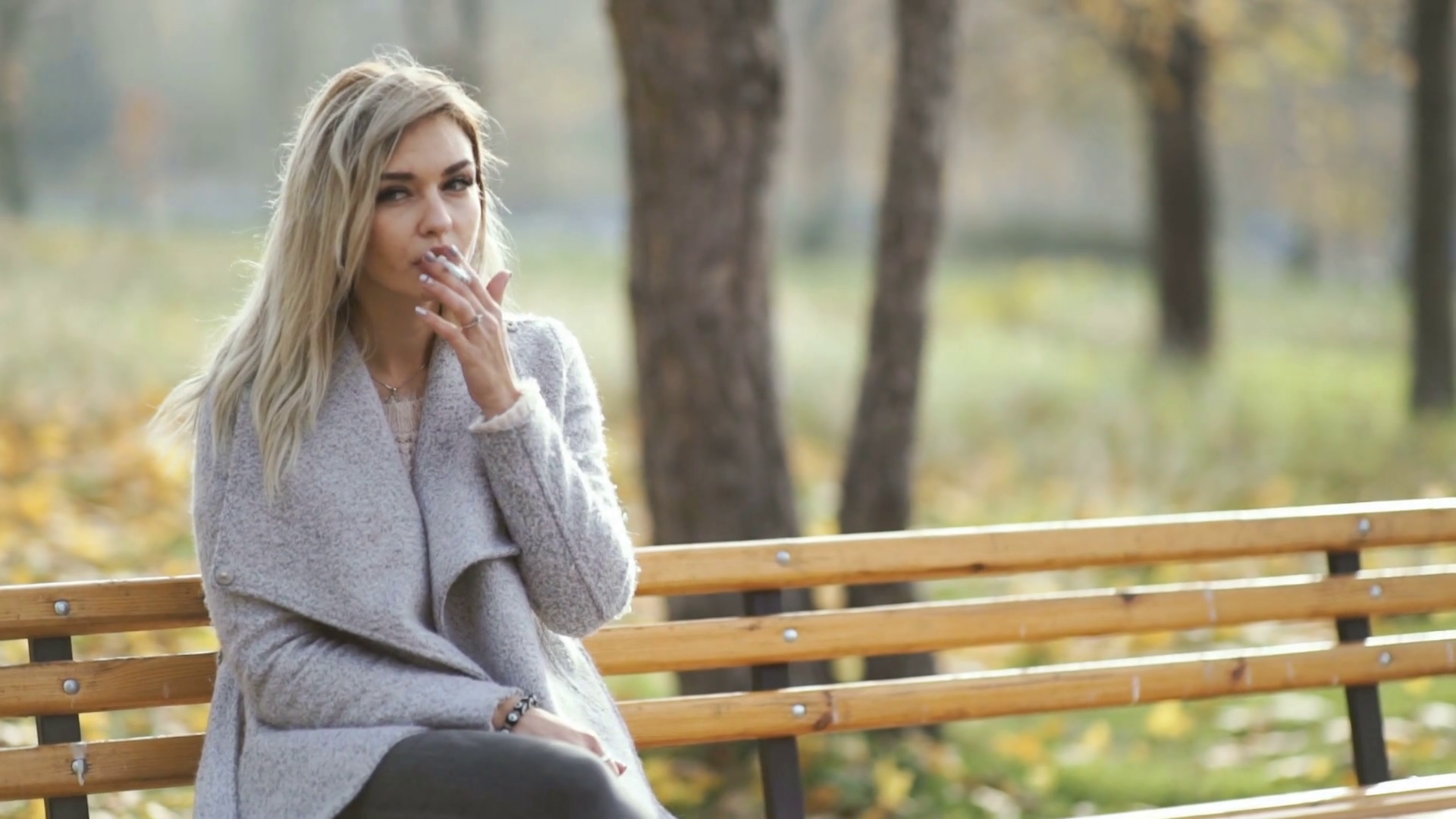 business woman smoking cigarette Elegant professional enjoying a break in the park. Autumn ambiance