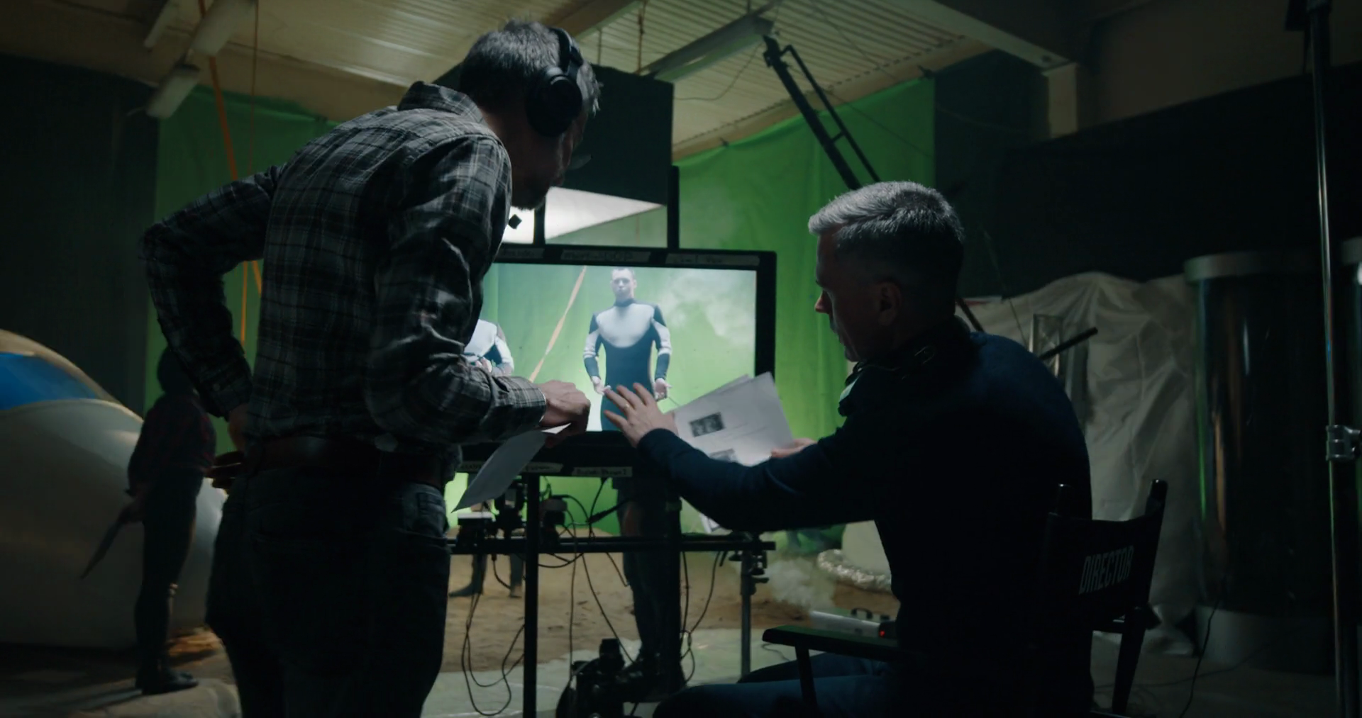 Medium shot of a director giving instructions to film crew member while  actors preparing in the background