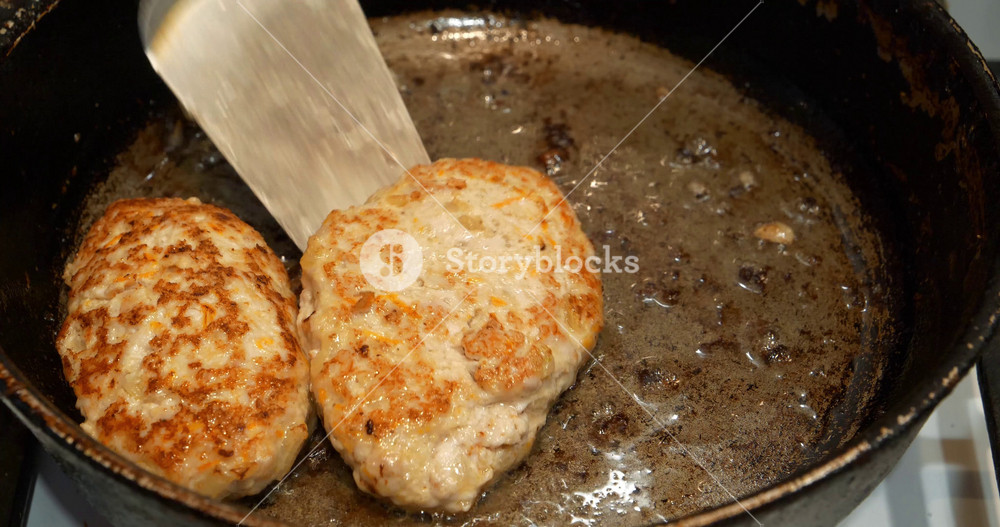 Meat cutlets were fried in a frying pan. The cook takes the meat patties out of frying pan after frying. Cooking, frying meat. Fatty, unhealthy food. Five meat patties are cooked on boiling oil in pan