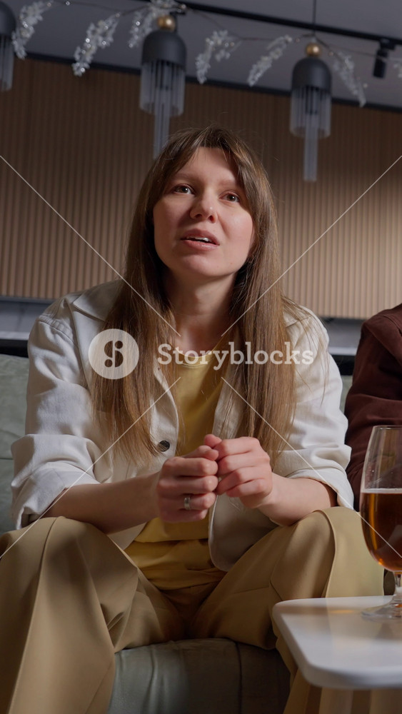Young woman enthusiastically watching a football game in a cozy living room setting, enjoying the match with focused expressions and vibrant