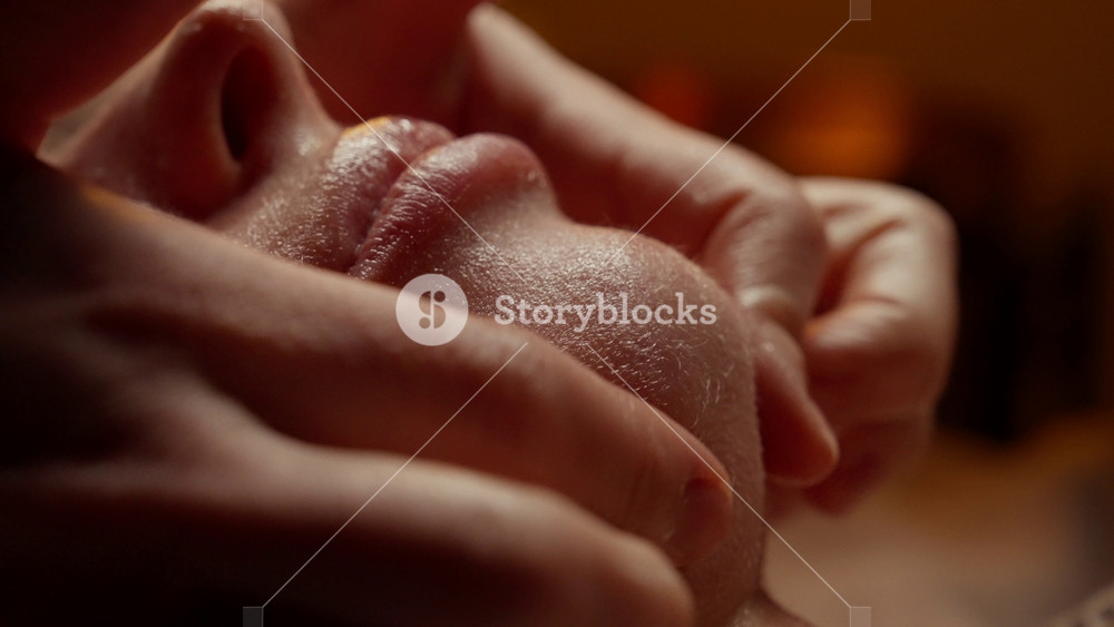 Close-up facial massage with gentle skincare treatment, soothing hand movements, and glistening skin in a relaxing spa environment focused