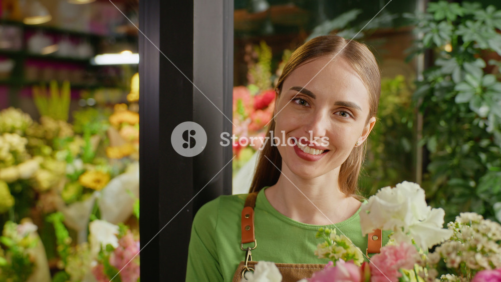 Portrait of smiling young adult Caucasian woman florist holding flower bouquet in shop. Video is perfect for small business marketing, florist promotions, and local retail advertisements