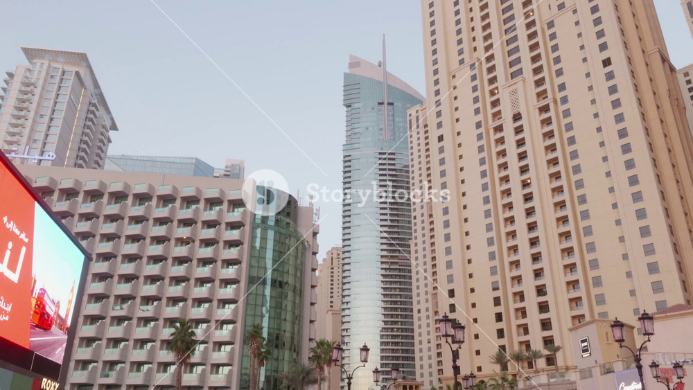 Dubai, United Arab Emirates - 20 Nov 2025. People walking along Dubai Marina promenade with palm trees and modern high rise buildings