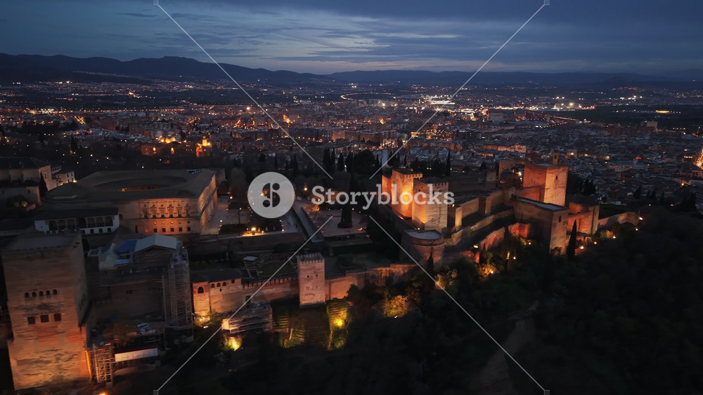 Illuminated walls and towers of the Alhambra palace in Granada, Spain. Night aerial view of the illuminated Alhambra fortress in Granada