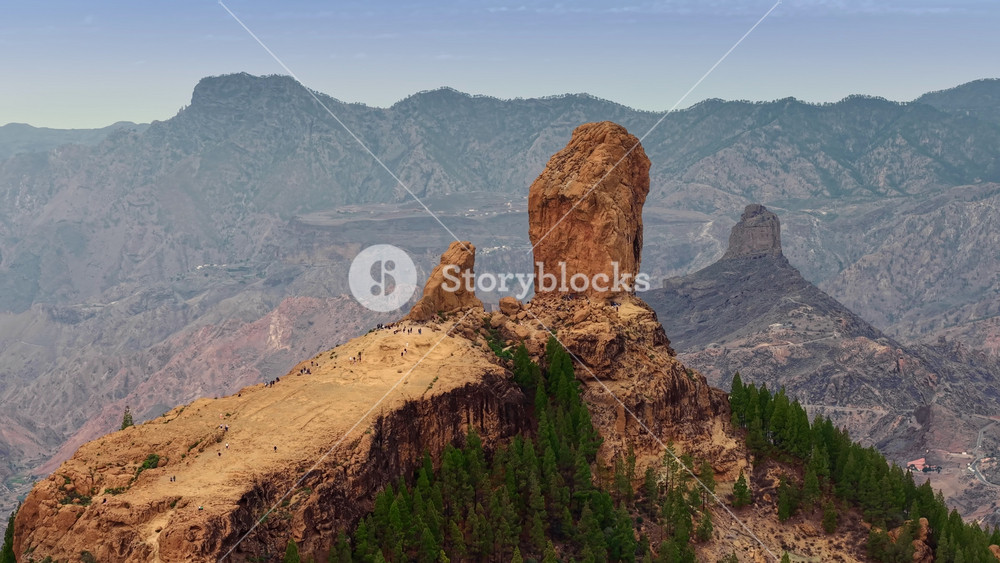Stunning view of Roque Nublo at sunset with dramatic rock formations and mountainous landscape in Gran Canaria. Aerial shot of tourists walk