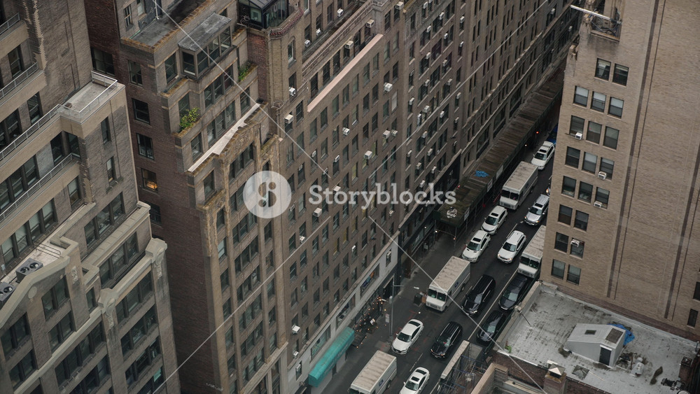 StreetLevel View Of Narrow Canyon Lined With Tall Brownstone Office Towers, Packed Traffic And Parked Cars, Delivery Van Maneuvering,