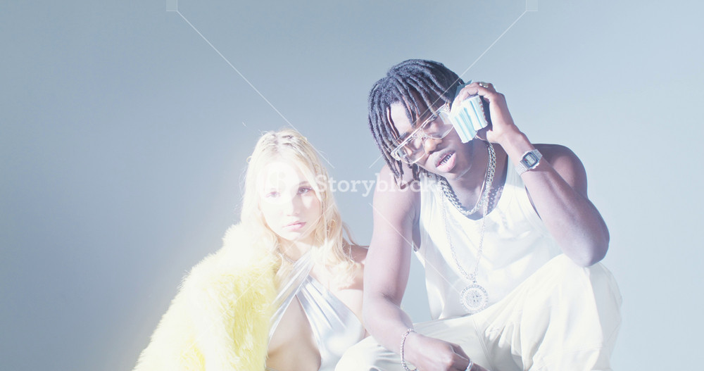 Photo shoot with money in the studio. A man and a woman of different nationalities look at the camera with serious look