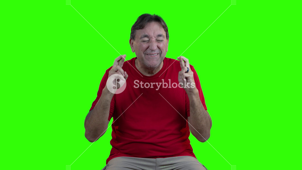 Man in red shirt crosses his fingers and hopes for the best, but ends up disappointed and sad when his wish doesnt come true, all set against a green screen background.