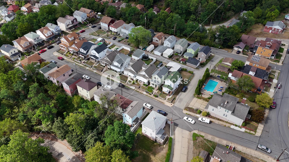Drone view of a Pennsylvania neighborhood with rows of houses, tree-lined streets, and backyards, capturing the look of a middle-class suburban community. 14803