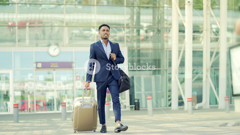 african, american tourist businessman walks public transport building with luggage on urban background a city street. Man in formal suit trip. Business traveler pulling suitcase in airport terminal