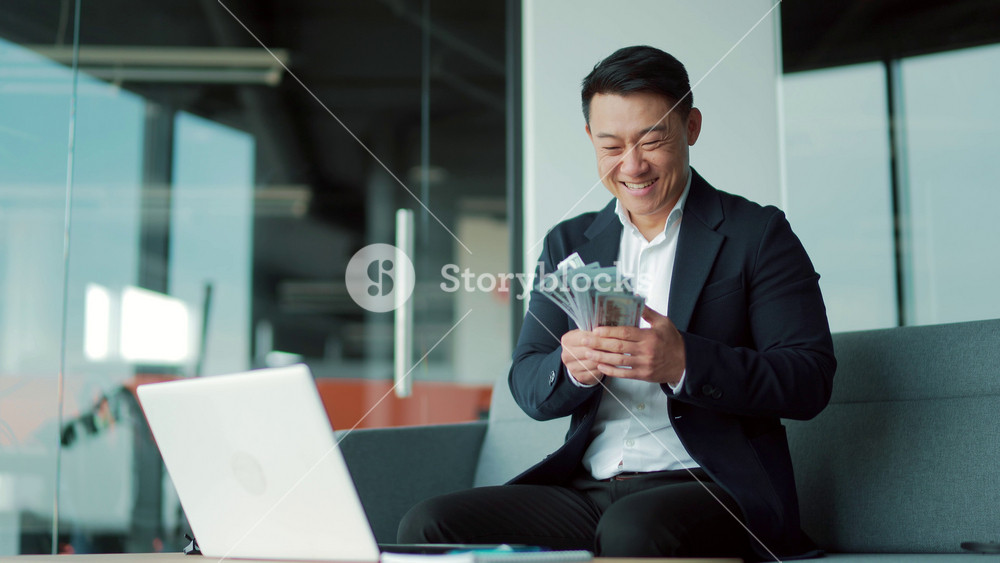 Happy successful asian businessman counts, waves, throws, money in office looking at camera Winner success in betting stock market celebrating victory Indoor business man, worker employee entrepreneur