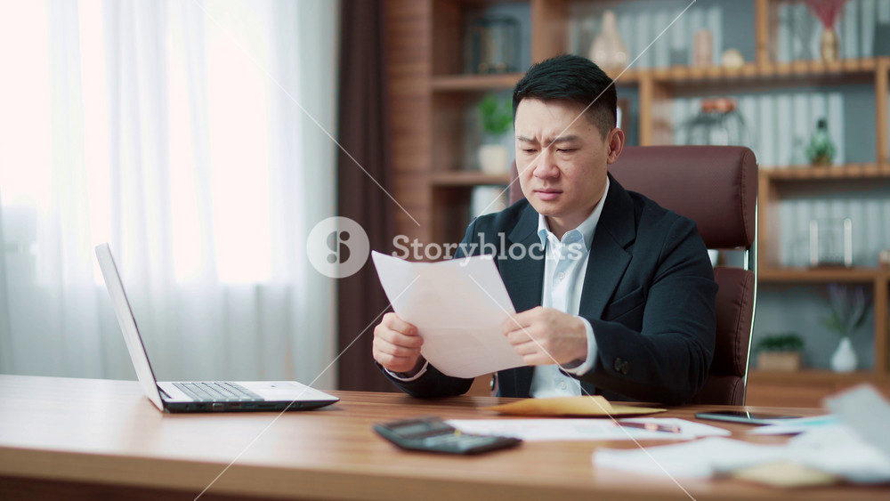 worried entrepreneur working and reading a letter with bad news. Shocked frustrated business man received, male manager employee unpacking banking notification, law order document at workplace. Asia