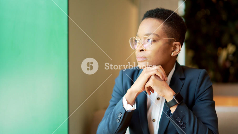 African American female thinking while sitting in a cafe, a serious thoughtful pensive business woman looking out the window. businesswoman employee entrepreneur sitting. startup and case resolution