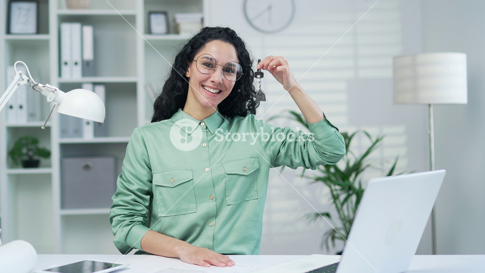 Woman realtor holding show key from new house apartment in modern office Concept for financial home loan or money saving for house buying, real estate and insurance Female designer or architect