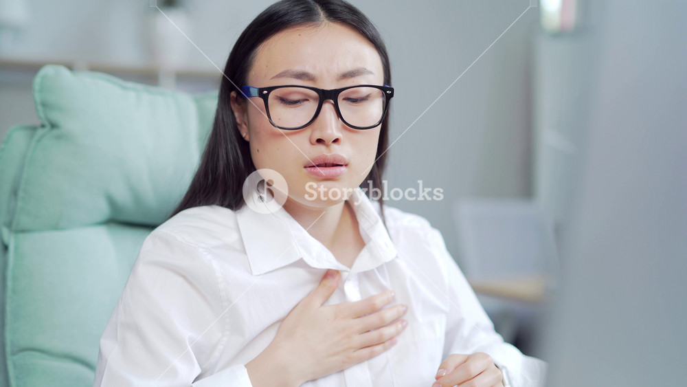 young asian female office worker having panic attack at workplace. business woman employee in the office shortness of breath, tired and sick having severe chest pain heartache at work indoor. Asia