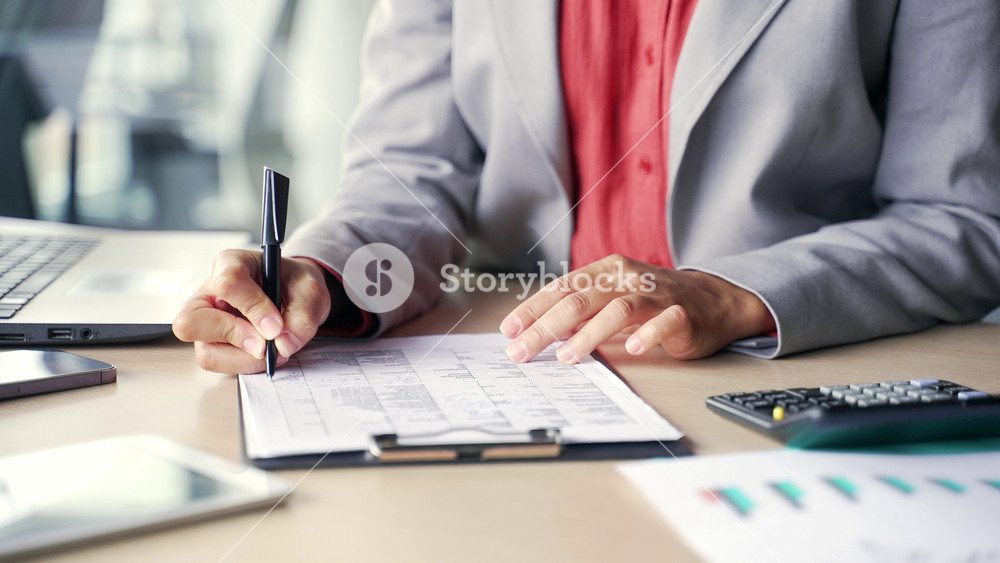 Close up of a female hand filling out documents with a pen. A young african american businesswoman is engaged in paper work, making financial calculations. A black woman fills out a blank tax form