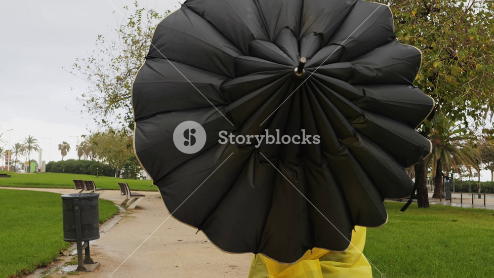 Business man tourist person with umbrella and raincoat on rainy european city street, lights reflecting, walking in Barcelona or Amsterdam