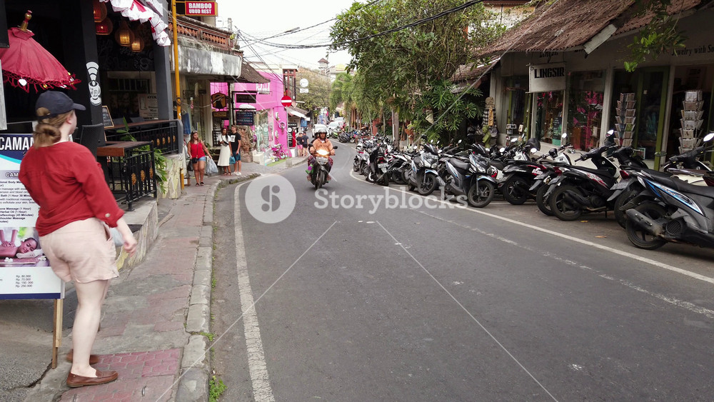Ubud, Bali, Indonesia - September 5, 2019: People walking and cars and motorcycles driving by in a busy street of the popular tourist town