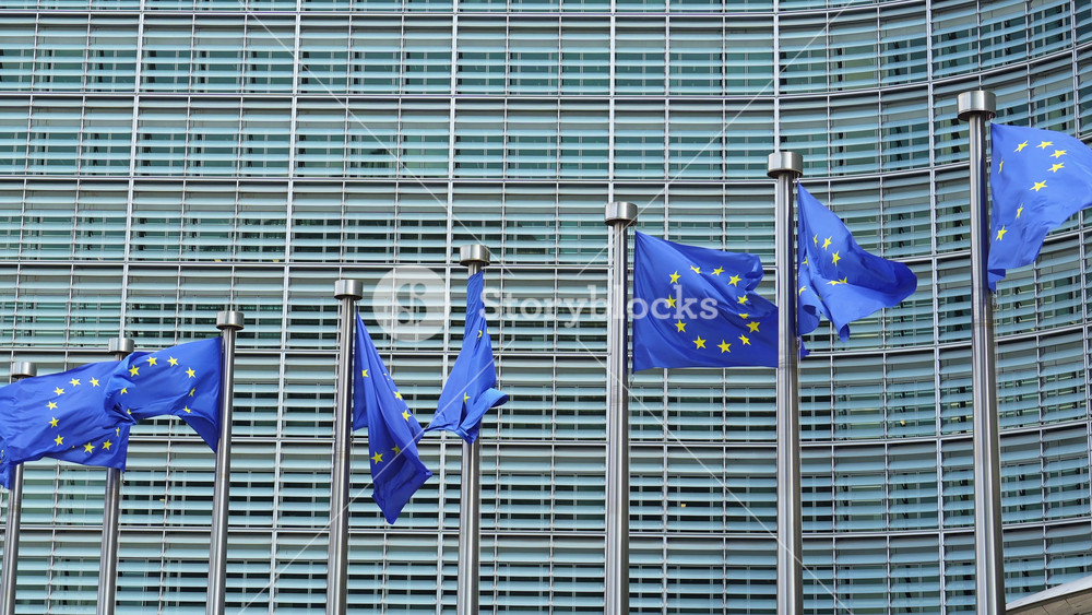 Row of European Union Blue Flags and Berlaymont Building, Headquarters of the European Commission. City of Brussels, Belgium. Slow Motion