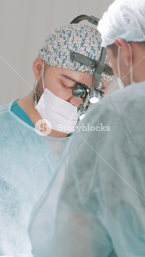 Two professional doctors in medical masks and clean uniform perform an operation. Action. Concept of healthcare and medicine.