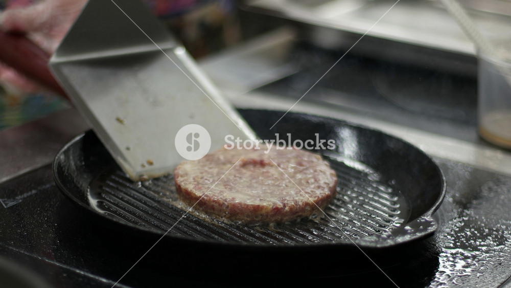 Flipping burger meat on hot pan. Media. Footage of traditional American hamburger cooking on kitchen at home. Close up video clip of fresh