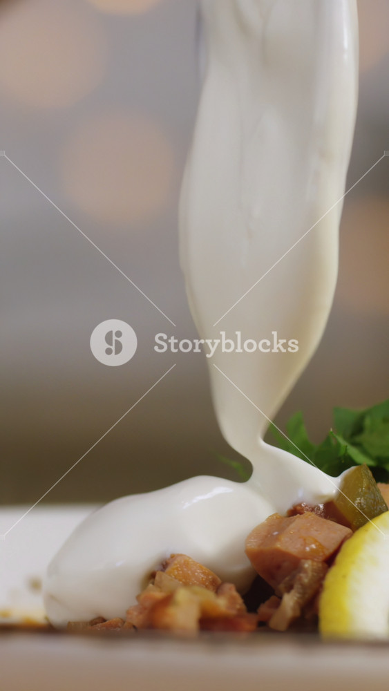 Close-up of some person's hand adding sour cream at the bowl with solyanka. Stock footage. Russian solyanka soup with meat, sausages and