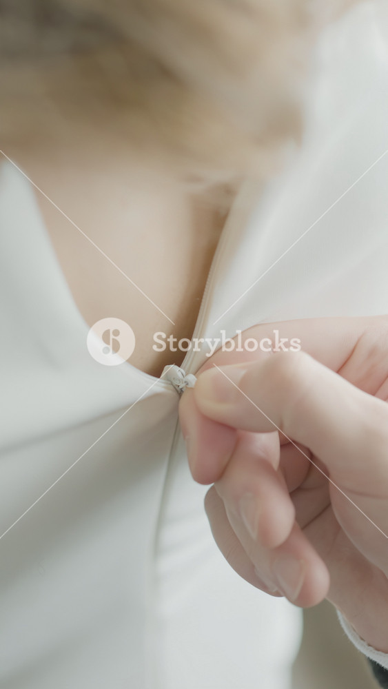 Husband buttoning dress on bride. Action. Close-up of husband helping to fasten bride's dress. Husband romantically fastens dress on wife