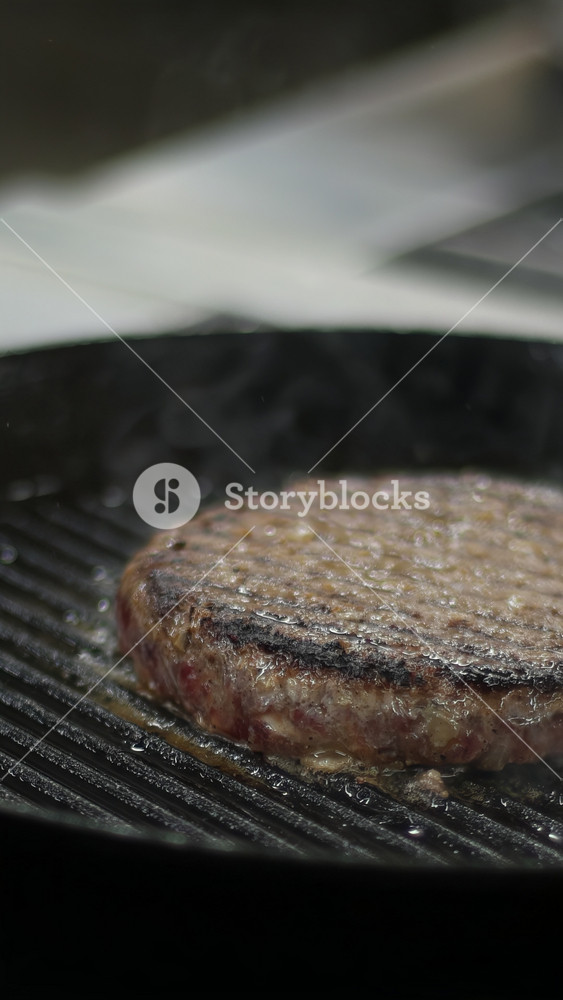 Flipping burger meat on hot pan. Media. Footage of traditional American hamburger cooking on kitchen at home. Close up video clip of fresh