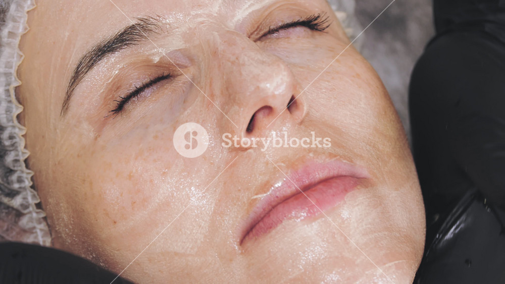 Rejuvenating facial massage session using honey for nourishment and lymphatic drainage. Modern skincare technique for adult women.