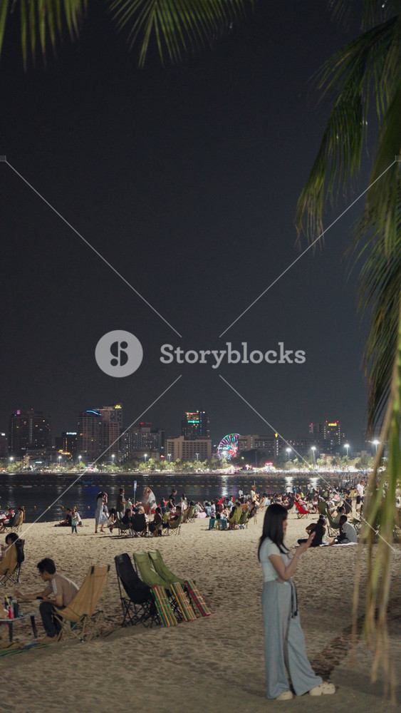 Pattaya, Thailand - May 1, 2026: Scenic nighttime footage of Pattaya Beach, Thailand, featuring the illuminated coastline, calm sea, city skyline, and people enjoying the tropical beach after sunset.