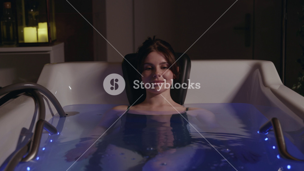 Smiling happy attractive woman in spa jacuzzi. Care about health. Body rest. Relaxing enjoy time. In dark room. Modern spa clinic. Slow