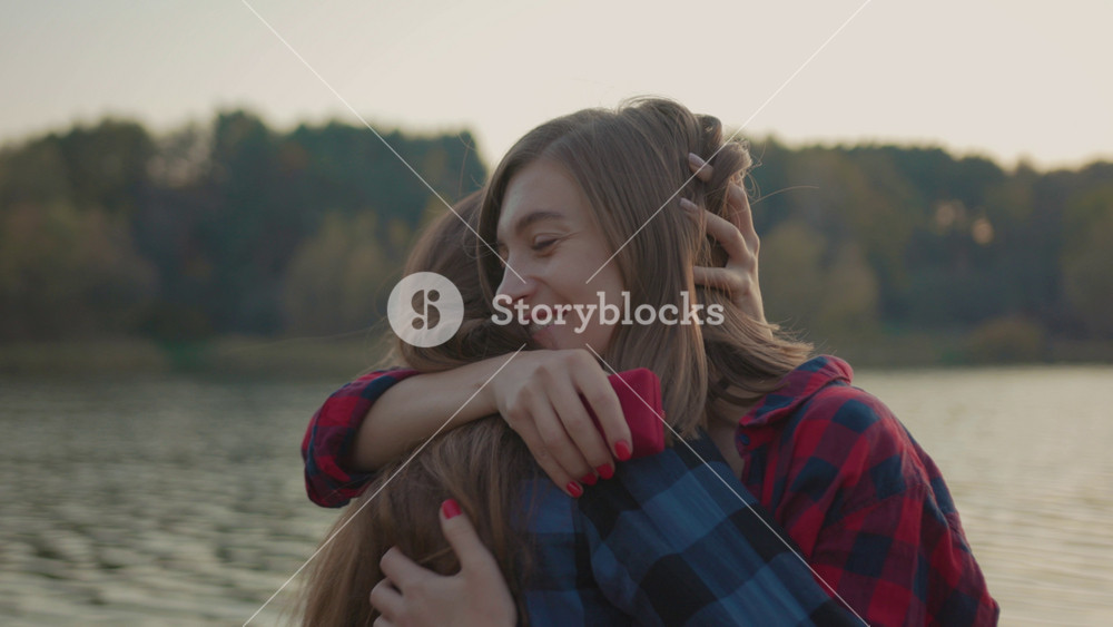 Just married happy woman hugging her girlfriend holding engagement ring crying of happiness exciting love moments on the river bank