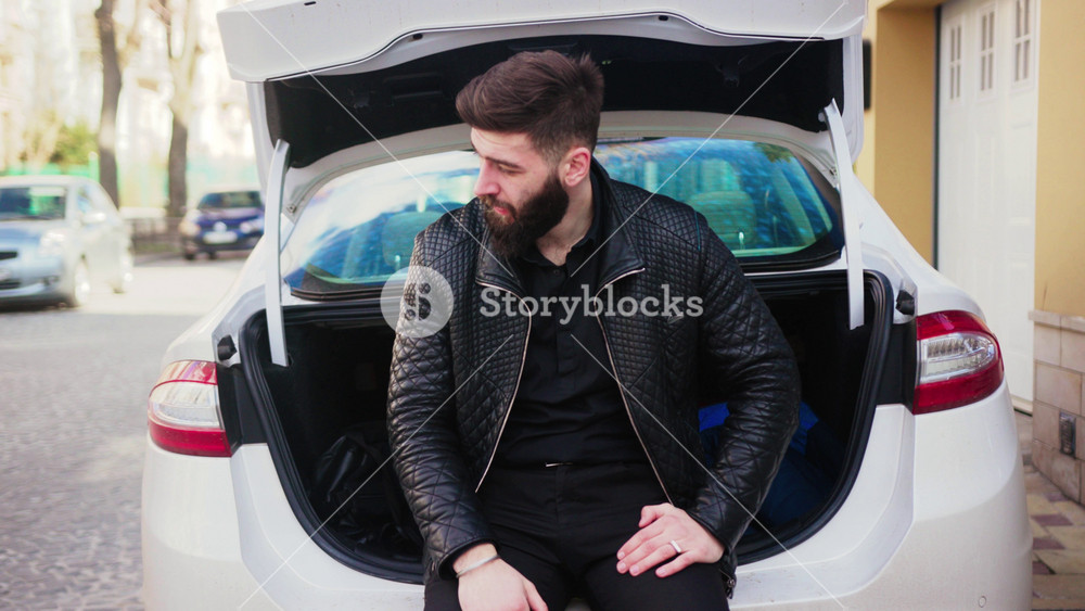 Portrait young man sitting near car trunk look at camera smile travel auto male man transportation young handsome guy leisure lifestyle