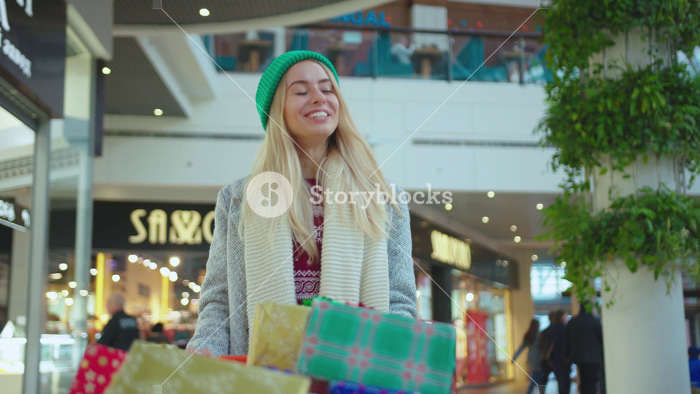 NEW YORK - April 5, 2019: Happy young attractive woman walking with Christmas presents boxes in cart on shop mall portrait smile shopping