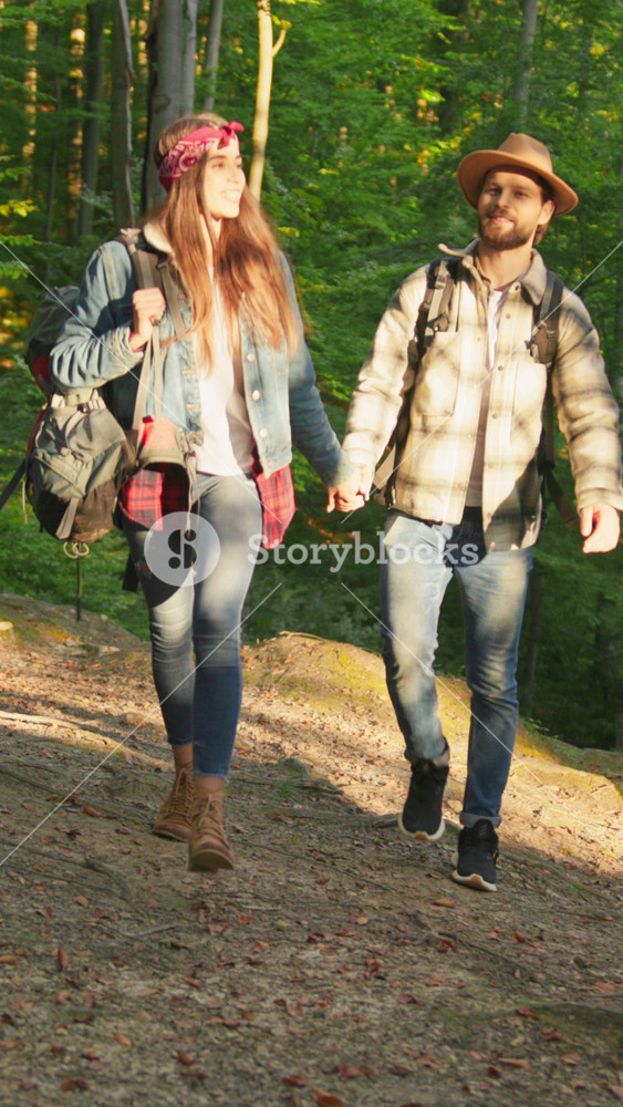 Handsome caucasian man with woman holding hands wearing hevay tourist backpack rucksacks walking in forest jungle. Traveling couple. Family