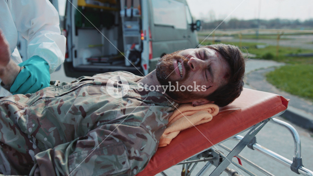 Footage of young bearded man in military clothes wounded by gunshots in fight for Ukrainian capital. Ambulances for evacuations in