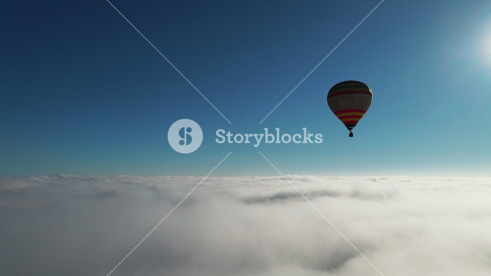 First person aerial view of beautiful air hot balloon flying high in the clouds during sunny hot weather. Scenery, skyline. Adventure