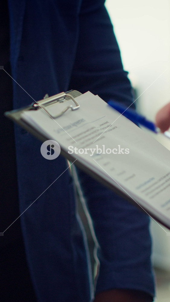 Vertical video Showroom dealer completes paperwork after selling vehicle, shaking hands with buyer and offering car keys. Salesman in