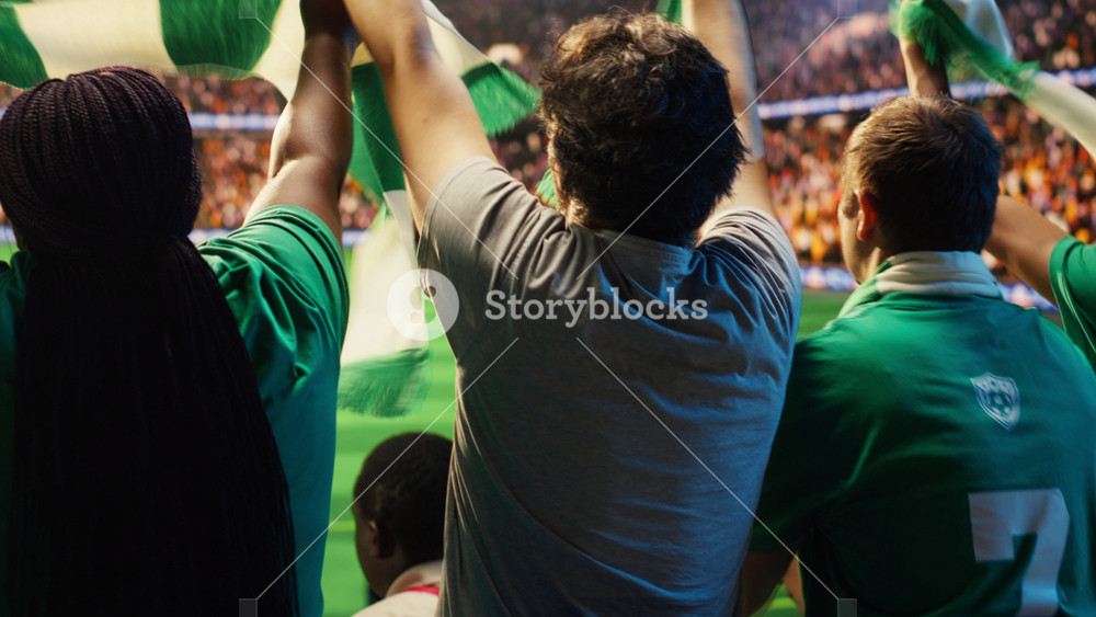 Close up of football fans clapping together in stadium tribunes during live match. Rear view of supporters applauding, creating loud chant