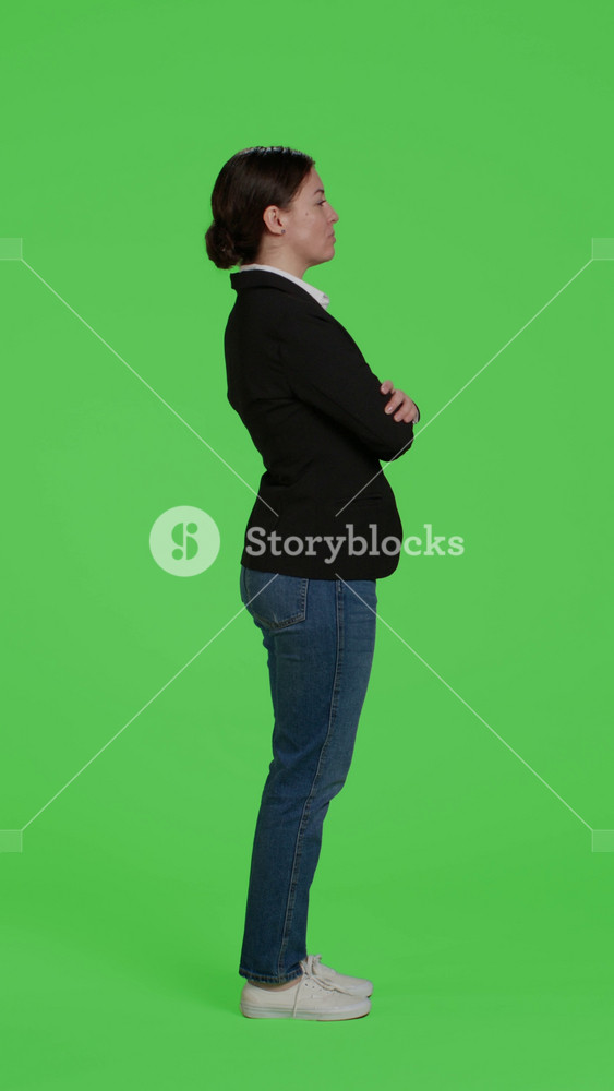 Vertical video: Profile of young businesswoman acting confident wearing suit, being friendly and stylish over full body greenscreen. Female