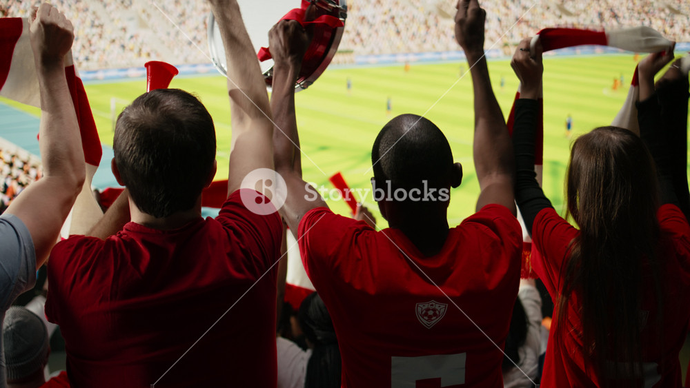 Back view of multigenerational sports fans in the supporter section watching live football match with pride and passion. Chanting fans