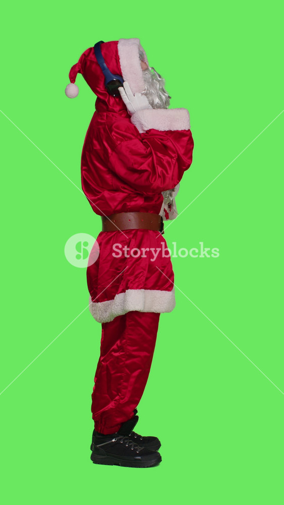 Vertical video Profile of saint nick having fun with music, listening songs on headphones and dancing in red festive suit. Young man