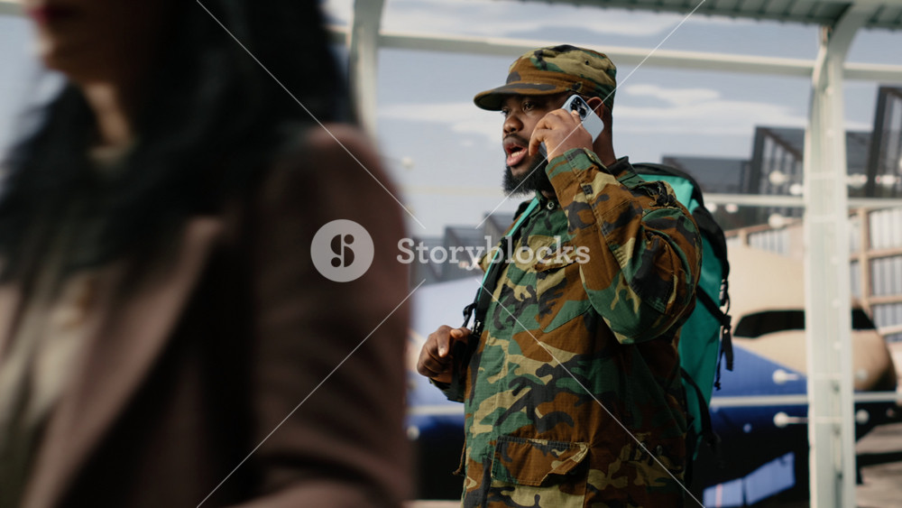 Army soldier doing mobile phone call in airport, preparing for homecoming. African american military man in camouflage clothing talking on
