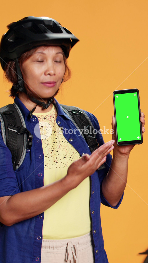 Woman holding chroma key green screen smartphone, showing location of upcoming delivery order. Courier preparing to ride bike to client