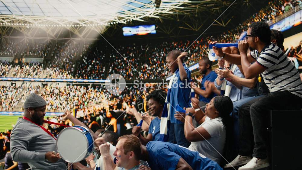Blue soccer supporters cheering together in crowded stadium during live football match in the supporter section. Passionate sports fans