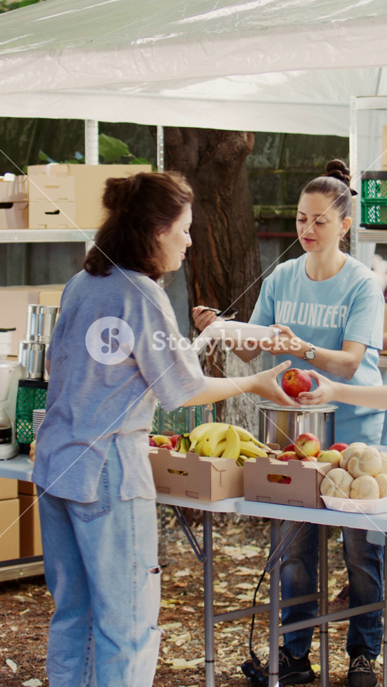 Vertical video At charity food drive, volunteers share provisions and food with the homeless. Young people offer their time to feed the