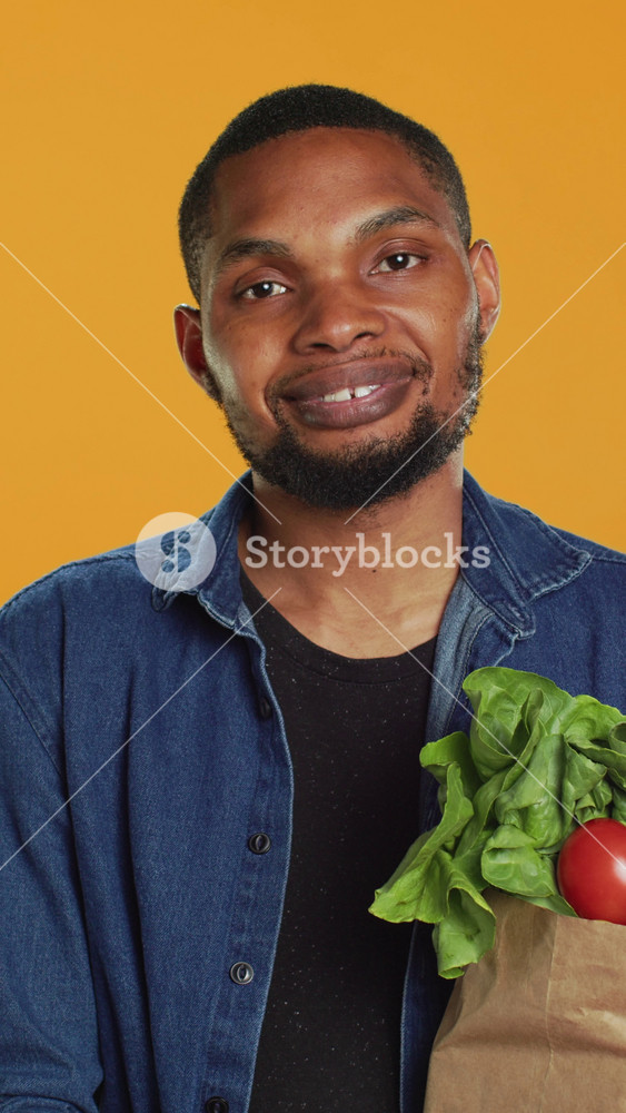 Vertical Video Portrait of smiling model carrying bag full of fresh bio groceries, buying locally grown organic fruits and vegetables from