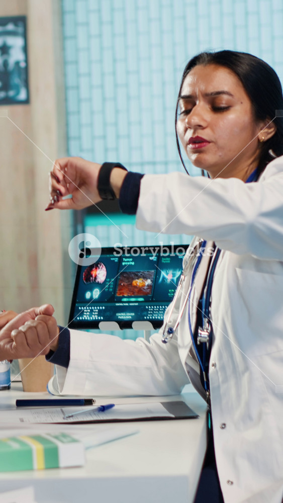 Vertical Video Medic cardiologist monitoring the heart rate of an indian patient, health app on smartwatch during check up. Modern