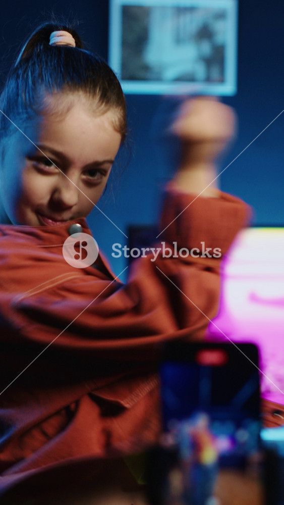 Children media star dancing in apartment, recording video with phone for gen z internet users. Happy girl filming herself with smartphone
